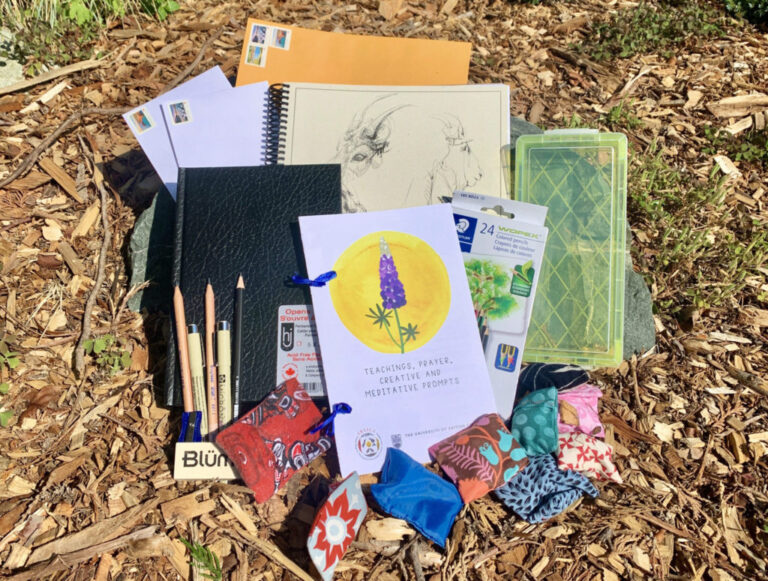 Photograph showing the ART & Justice Art Kits, containing pencils, sketchbooks, papers, bags, on a brown background